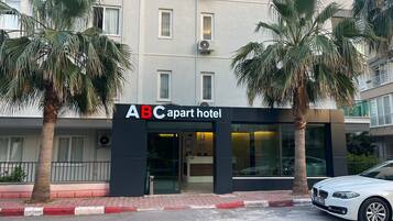 Ein Gebäude mit einem Schild, auf dem 'ABC apart hotel' steht, und Palmen davor.