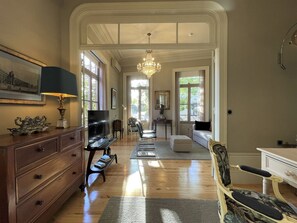 Un salon spacieux doté d’un parquet, d’un lustre, d’une télévision et d’un canapé.