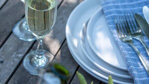 A table set with two glasses of white wine, a bottle, a plate with a fork and knife, and a napkin. - Chena Magica (Calera de Tango)
