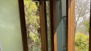 A bathroom with a bathtub, two candles, and a window with a view of greenery. - Chena Magica (Calera de Tango)
