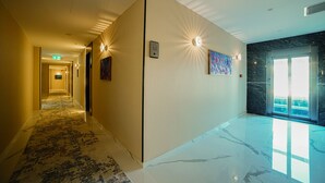 Et hotel med et korridor, gulvtæppe med mønster, marmor på gulvet, og et stort vindue med udsigt.