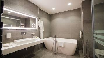 Un baño moderno con un espejo grande, lavamanos dobles, una bañera independiente y una cabina de ducha de vidrio.