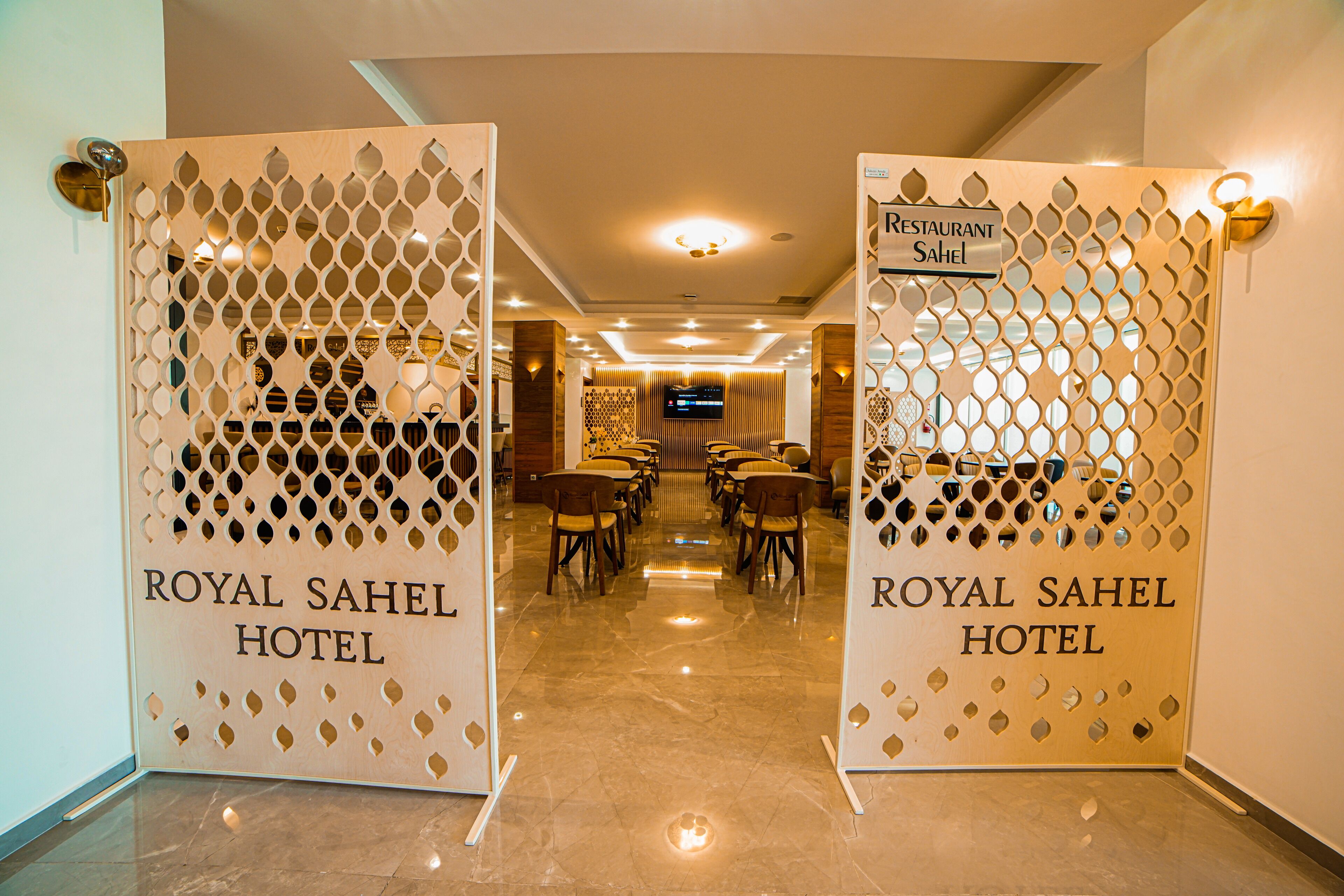 Entrada para o Hotel Royal Sahel, com decoração moderna e uma área de recepção visível ao fundo.