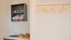 A kitchen with a built-in shelf holding dishes and a drying rack above it. - Krotiri View of Paros (Paros)