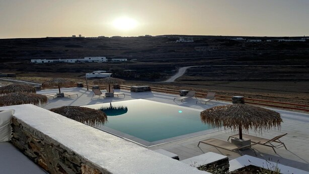 A rooftop pool with a clear view of the sunset, surrounded by lounge chairs and thatched umbrellas. - Krotiri View of Paros (Paros)