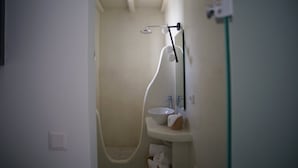 A small bathroom with a bathtub, a sink, and a mirror. - Krotiri View of  Paros (Paros)