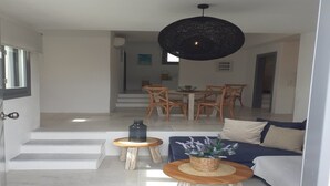 Een moderne woonkamer met een bank, een salontafel en een eetgedeelte met een tafel en stoelen.