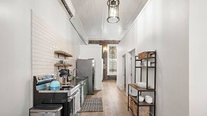 A narrow kitchen with a built-in oven, a refrigerator, and a sink. There is a wooden floor and a patterned rug.