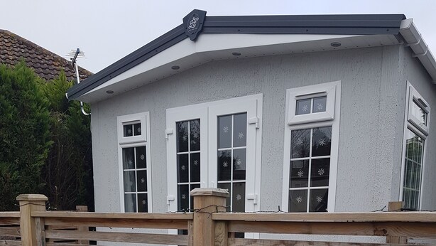 A house with a white exterior, a sloped roof, and a wooden fence in front. - Lovely 2-bed Chalet at Robinhood Retreat Free Park (Newark)