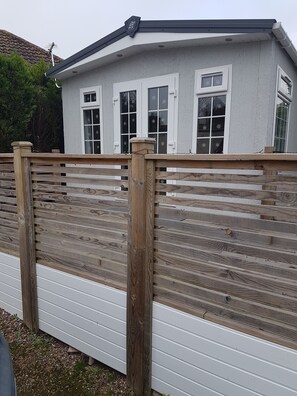 A house with a white exterior, a sloped roof, and a wooden fence in front. - Lovely 2-bed Chalet at Robinhood Retreat Free Park (Newark)