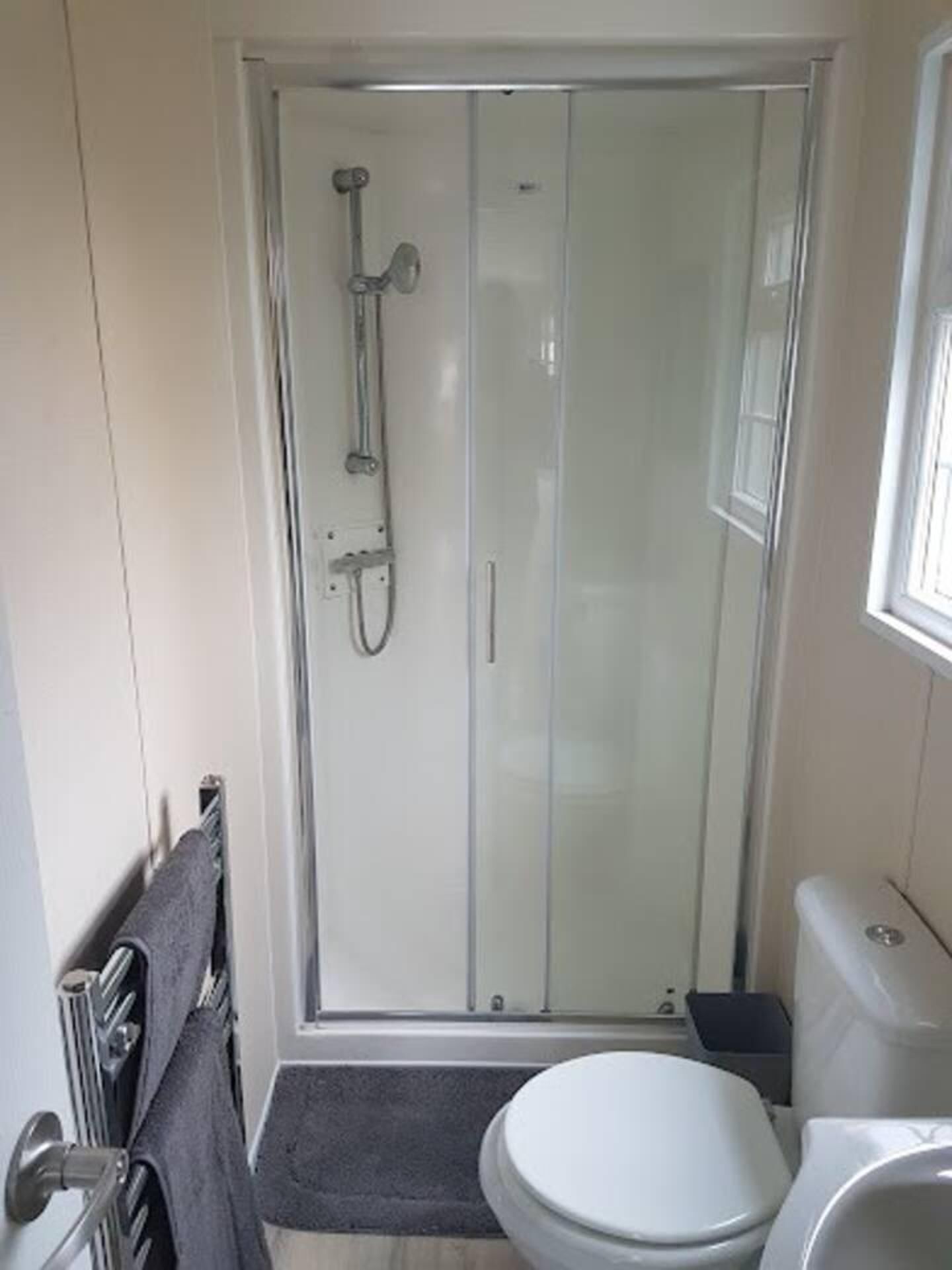A small, modern bathroom with a glass shower enclosure, a toilet, and a sink.