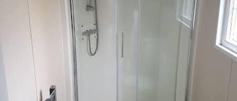 A small, modern bathroom with a glass shower enclosure, a toilet, and a sink.