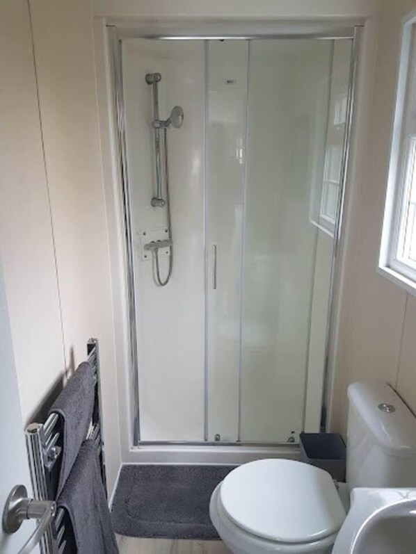 Um banheiro pequeno e moderno com box de vidro, vaso sanitário e pia.