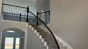 A grand staircase with a curved design, white steps, and black railings.