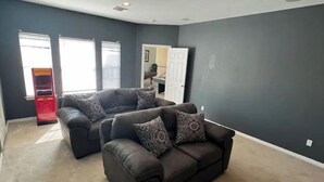 A living room with two dark brown sofas, patterned cushions, and a popcorn machine.