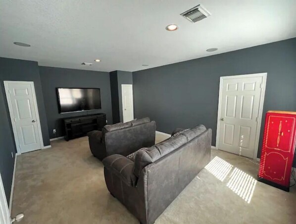A living room with dark walls, a flat-screen TV, a sofa, and a red cabinet.