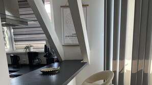 Una cocina moderna con encimera negra, una silla blanca y suelo de madera.