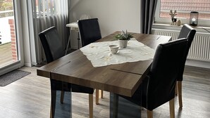 Un comedor moderno con una mesa de madera, sillas negras y vista a un edificio de ladrillo.