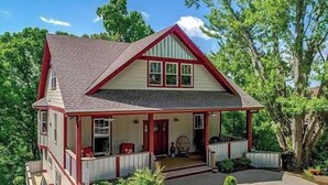 A two-story house with a red and white exterior, a front porch, and a driveway.