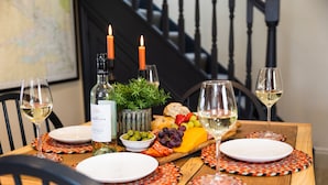 A wooden dining table with a cheese board, wine glasses, and candles.