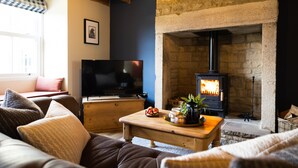 A cozy living room with a stone fireplace, a television, and comfortable seating.