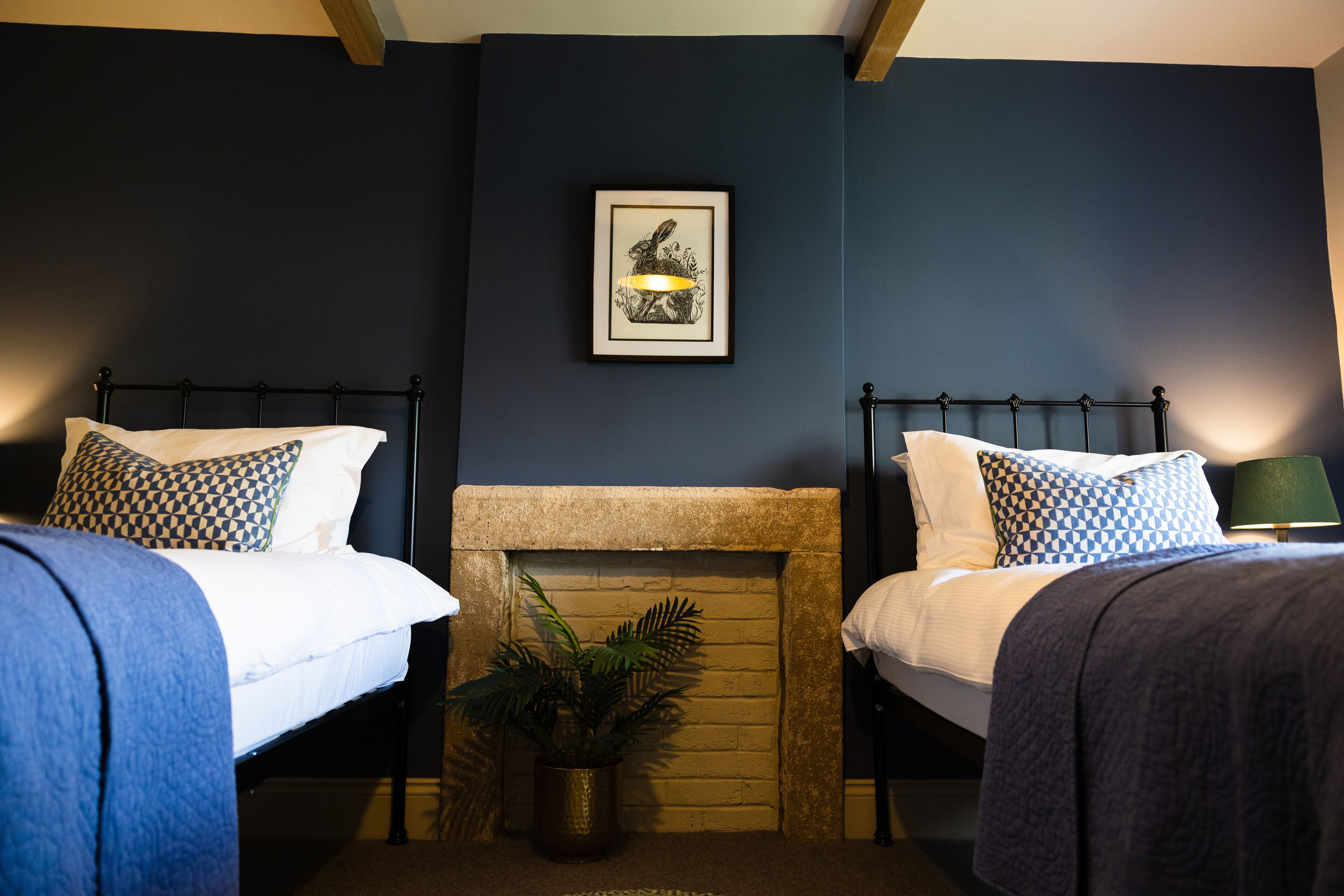 A room with two beds, a fireplace, and a framed picture on the wall.