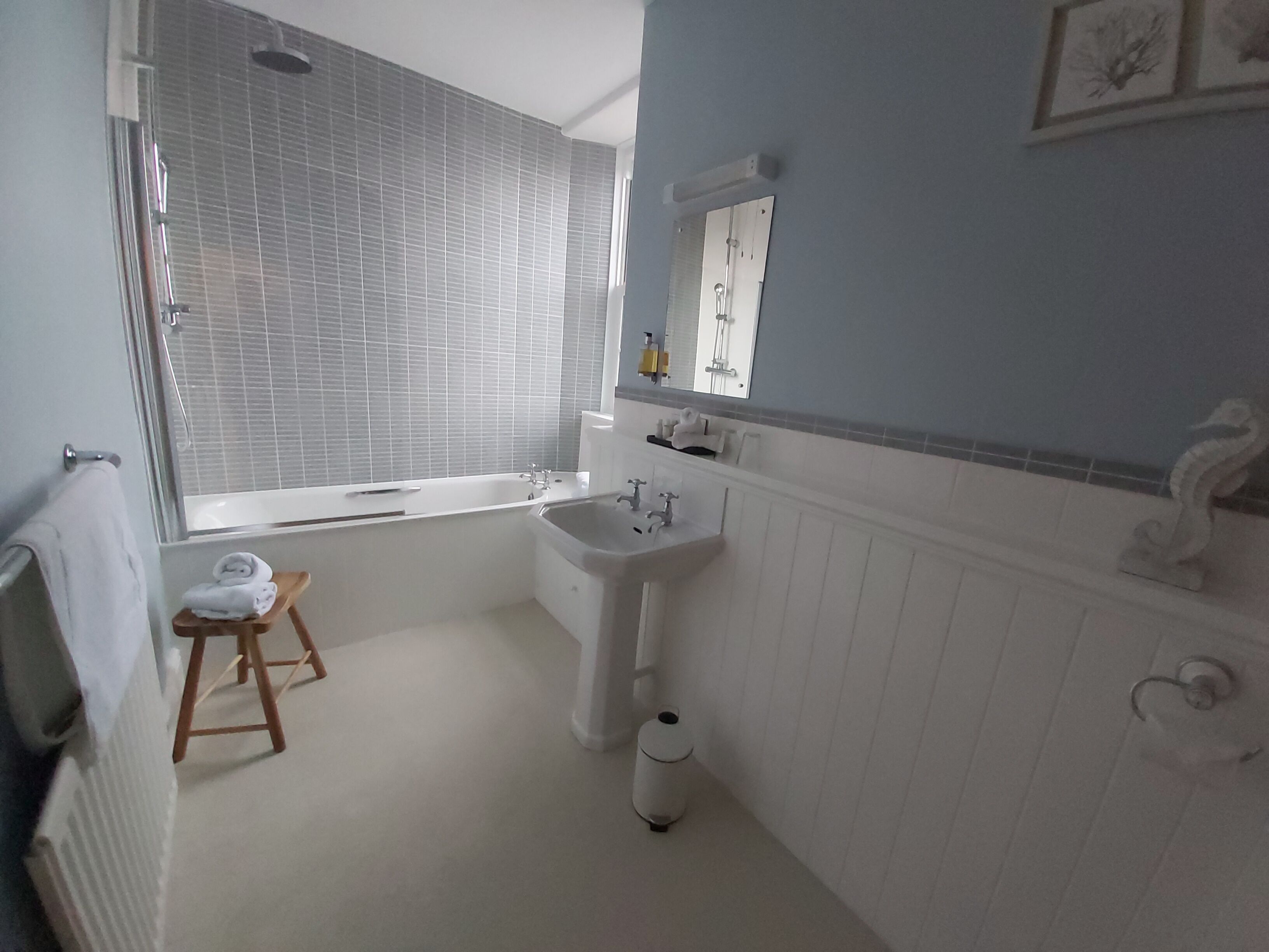 Un baño con bañera, lavabo y un taburete pequeño.