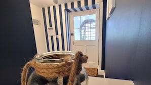 A room with a striped wall, a door with a window, and a table with a glass jar filled with rocks. - Llys Aeron Guest House (Aberaeron)