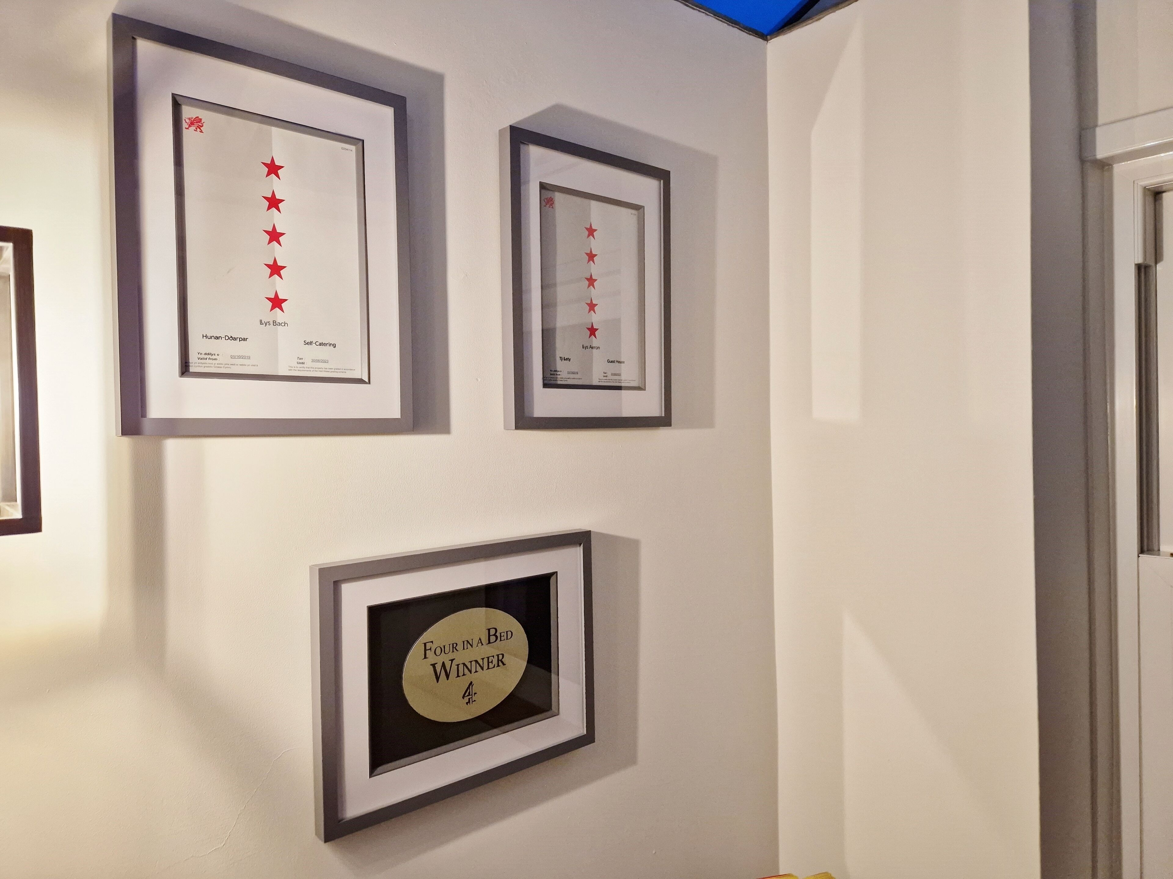 A wall with three framed awards and a framed certificate.