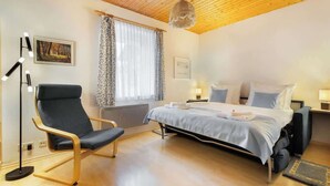 Une chambre à coucher moderne avec un plafond en bois, un lit avec une literie blanche, une chaise noire et une lampe sur pied.