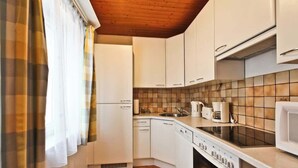 Une cuisine de taille réduite, avec des meubles blancs, une cuisinière, un four à micro-ondes et un évier.