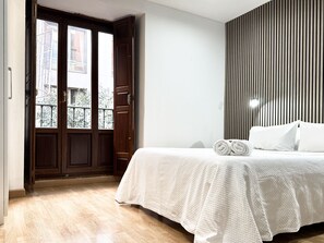 Habitació d'hotel amb una porta de fusta, un llit amb roba de llit blanca i una paret estriada.