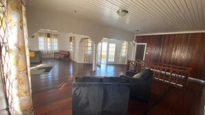 Ein geräumiges Wohnzimmer mit einem großen grauen Ecksofa, Holzboden und einer Holzbank an der Wand.