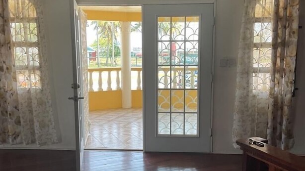 Ein geräumiges Zimmer mit Holzboden, einer Couch und Blick auf einen Balkon mit Geländer.