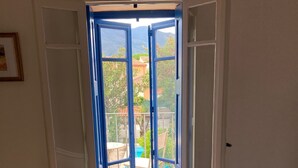 Un dormitorio con cama, radiador, y una puerta que da a un patio exterior con mesa y sillas.