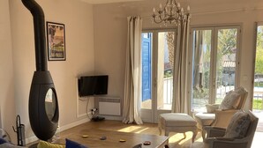 Una sala de estar con chimenea, un sofá, un televisor y vistas al exterior.