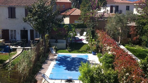 Zona residencial con piscina rodeada de vegetación y casas con techos de tejas rojas.