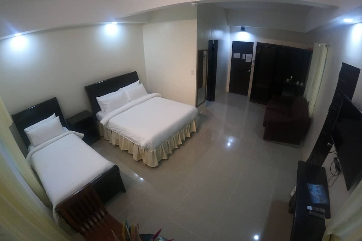 A hotel room with two beds, a TV, and a desk.