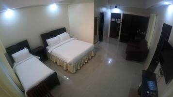 A hotel room with two beds, a TV, and a desk.