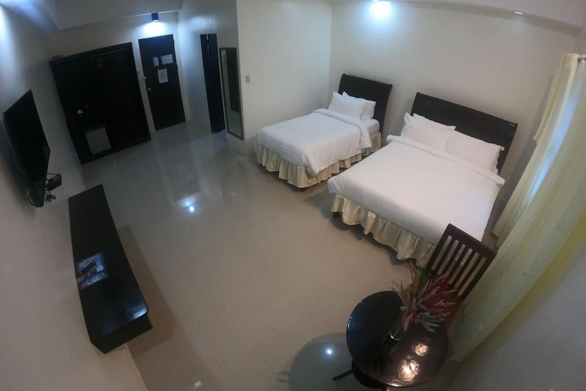 A hotel room with two beds, a desk, and a chair.