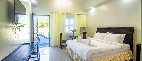 A hotel room with a bed, a desk, a chair, a TV, and a view of the outdoors.