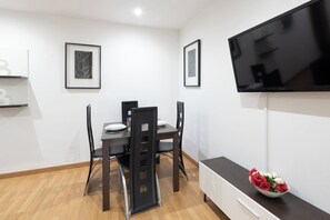 Uma sala de jantar moderna com TV, obras de arte emolduradas e um arranjo floral.