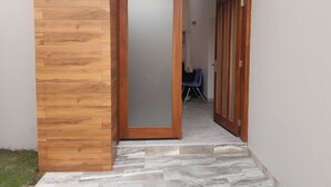 A wooden exterior wall with a door leading to a tiled interior. - Accra Cozy Retreat With 2 Bedrooms (Santeo)
