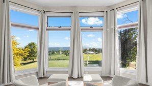 Una stanza con ampie finestre e vista su un paesaggio verde, con due poltrone.