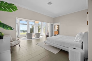 Une chambre moderne avec un grand lit, un bureau, une chaise et une vue sur l’extérieur.