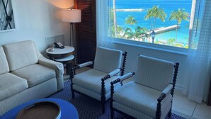 A hotel room with a view of the ocean, a round table with a lamp, two armchairs, and a small side table with a phone. - FULL RESORT ACCESS! Marriott Two Bedroom Suites with full kitchen (St Thomas)