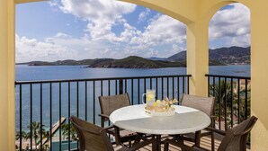A balcony with a table and chairs, overlooking a body of water and distant hills. - FULL RESORT ACCESS! Marriott Two Bedroom Suites with full kitchen (St Thomas)
