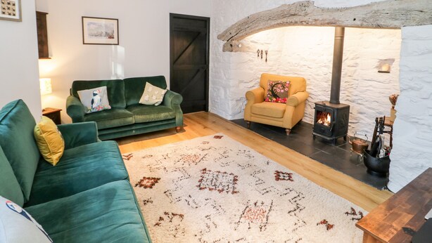 A cozy living room with a green sofa, a yellow armchair, and a fireplace. - Sea Chest (Conwy)