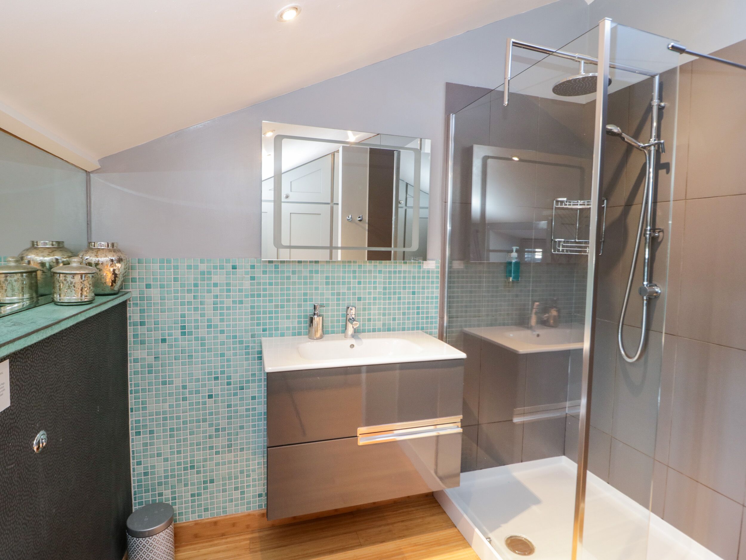 A modern bathroom with a glass-enclosed shower, a sink with a mirror, and a tiled backsplash.