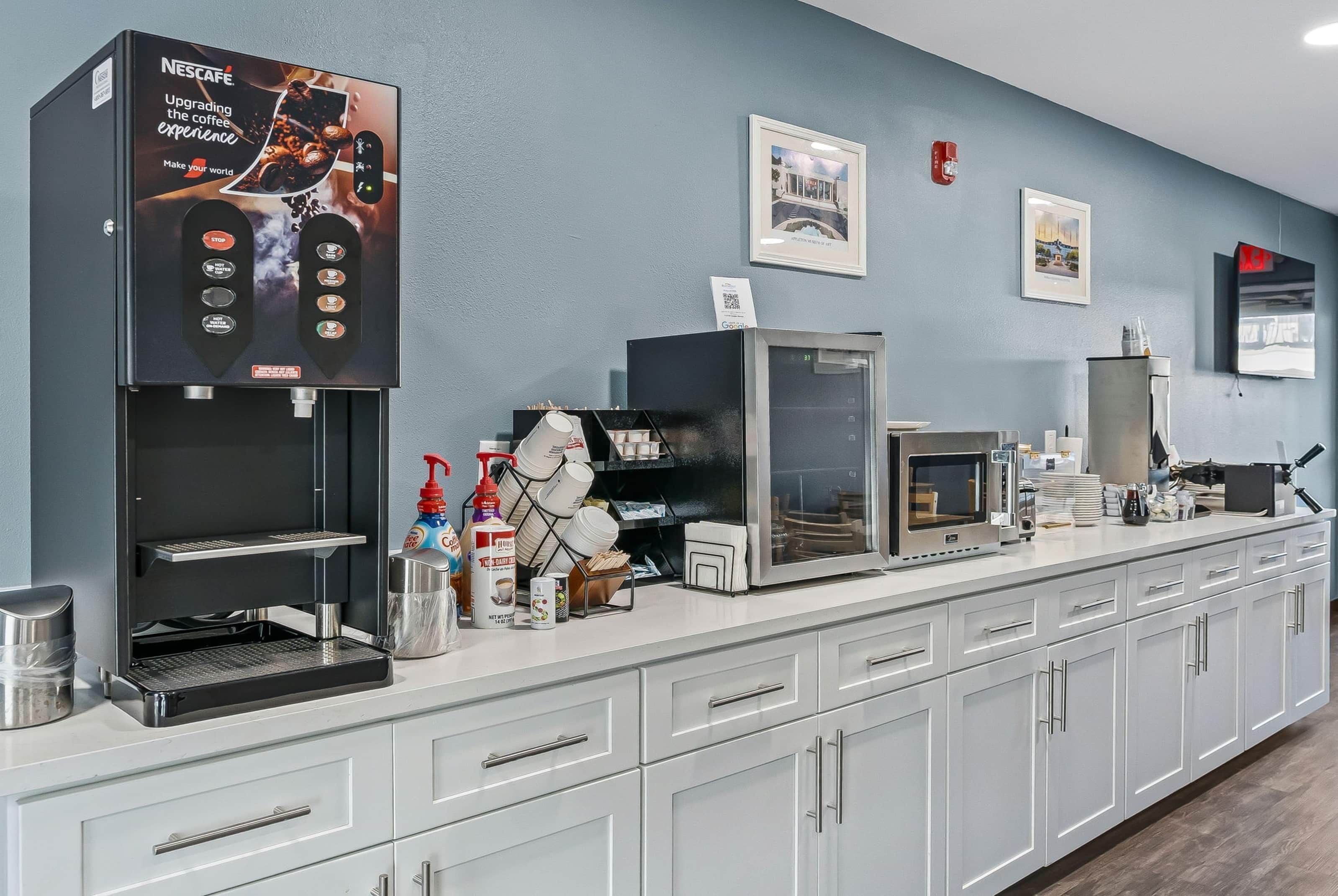 A modern coffee station with a Nescafe machine, a microwave, and various coffee-making accessories.